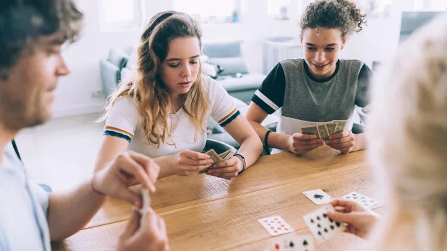 Familj spelar klassiskt kortspel vid köksbordet